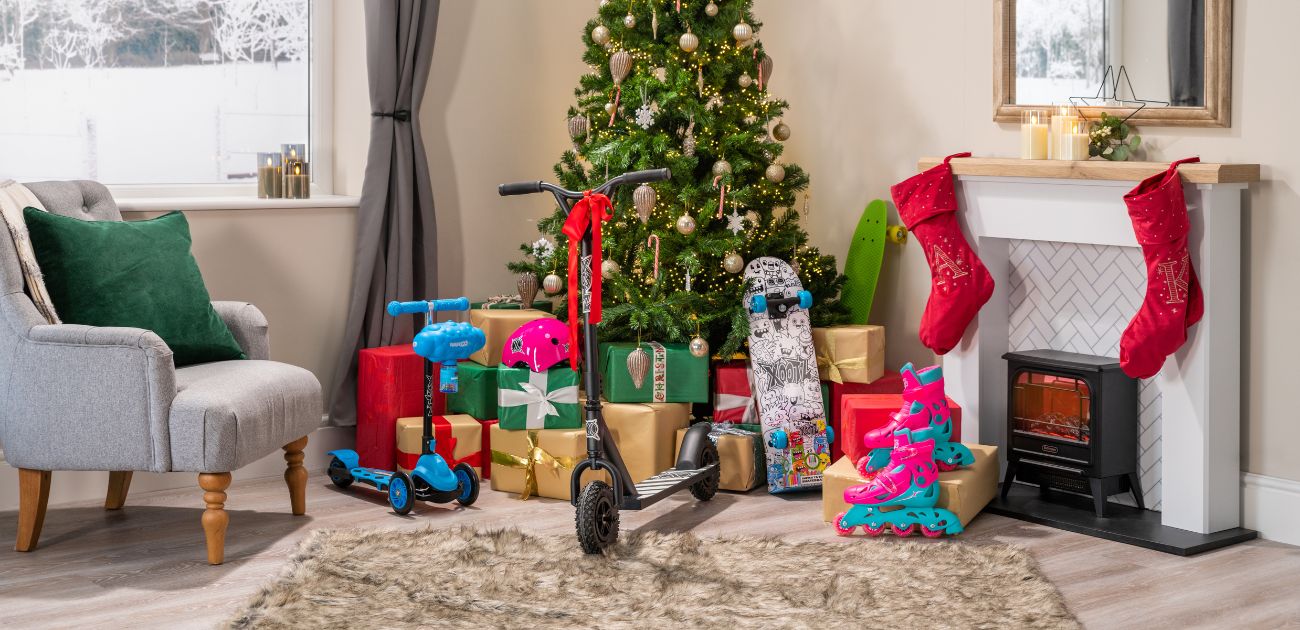 A photo of Xootz scooters, skateboards and roller skates in front of a Christmas tree.