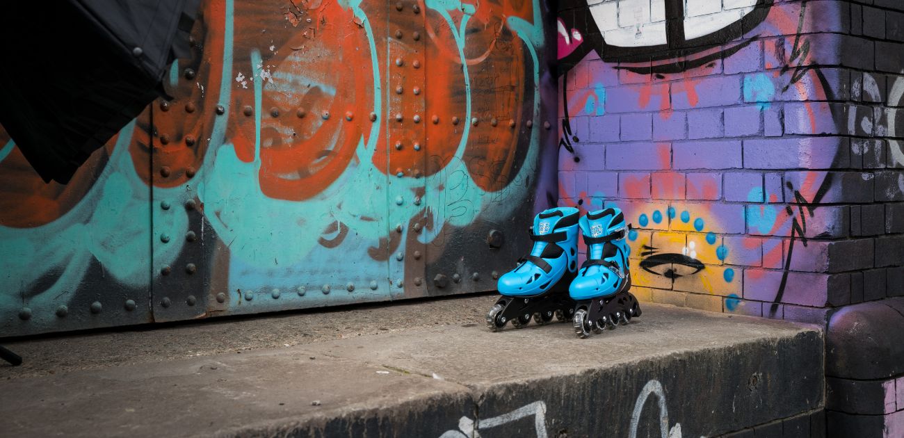 A photo of a pair of blue inline roller skates against a graffiti background