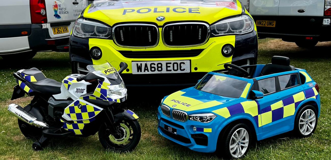 A photo of two Xootz ride ons decorated with police branding in front of a police car