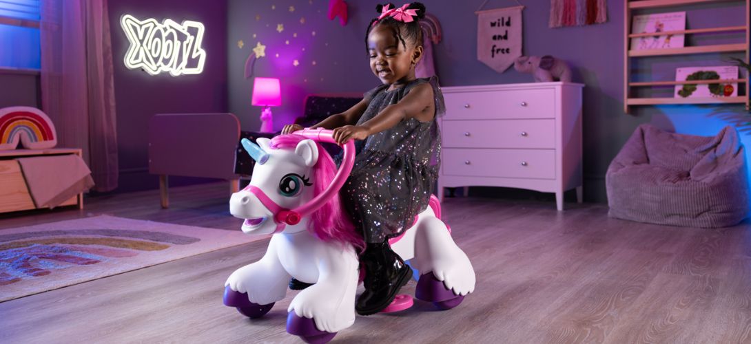 A photo of a girl riding a white electric unicorn ride on in her bedroom